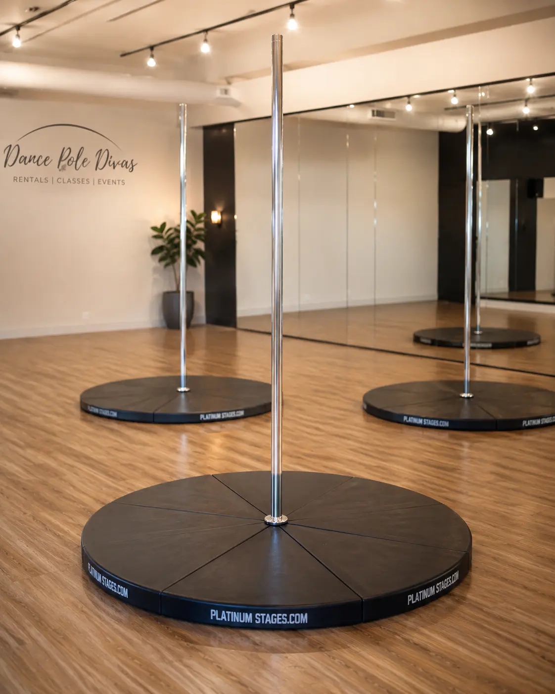 Chrome dance poles on round black stage bases in a mirrored open space